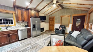 A spacious kitchen with wooden cabinets, a stainless steel refrigerator, and a built-in oven. There is a dining area with a wooden table and a leather couch.