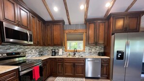 A modern kitchen with wooden cabinets, stainless steel appliances, and a patterned rug.