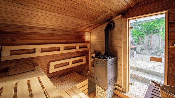 A wooden sauna room with benches and a sauna stove. - 10 minutes from Budapest Family apartment (Törökbálint)