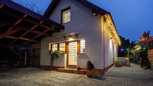 A two-story building with a covered patio area, a wooden bench, and potted plants. - 10 minutes from Budapest Family apartment (Törökbálint)