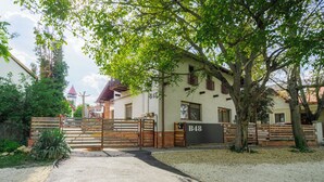 A gated property with a white building, a wooden gate, and a tree in front. - 10 minutes from Budapest Family apartment (Törökbálint)