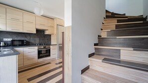 A modern kitchen with wooden cabinets, a stainless steel refrigerator, and a built-in oven. - 10 minutes from Budapest Family apartment (Törökbálint)