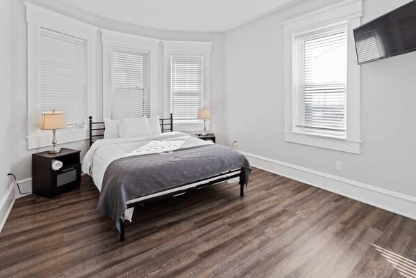 A bedroom with a bed, two bedside tables, and a TV mounted on the wall.