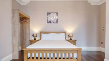 A bedroom with a wooden bed, two bedside tables with lamps, a wall-mounted artwork, and a wooden wardrobe.