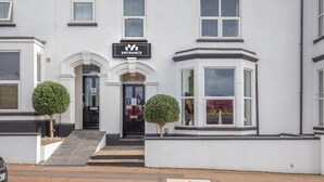 A building with a sign reading 'ENTRANCE' above the door, a small tree in front, and a window with a view. - Marlborough Hotel (Norwich)