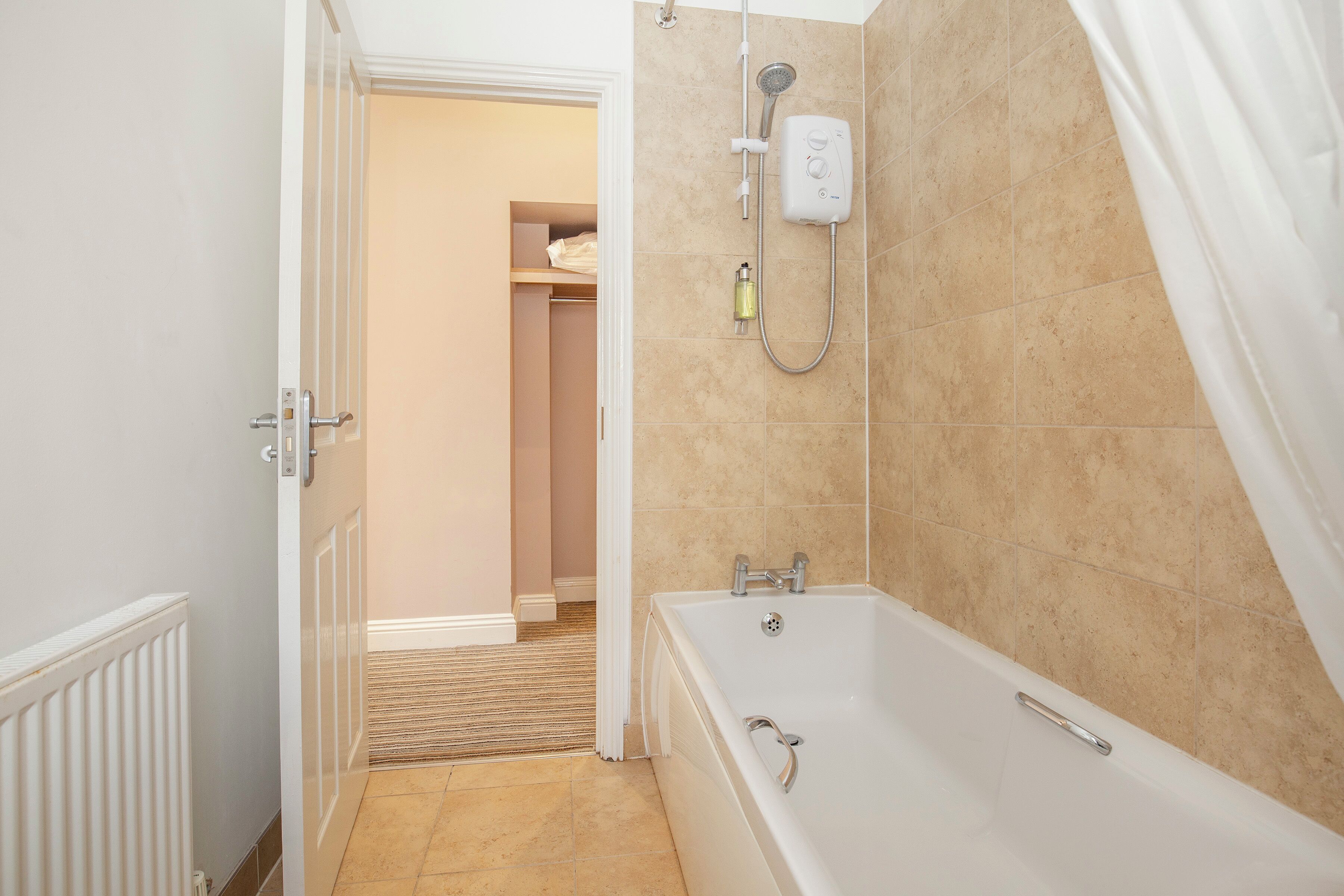 A bathroom with a bathtub, shower, and a towel rack.