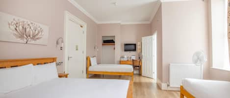 Quarto de hotel com duas camas, uma escrivaninha, televisão e janela com cortinas.