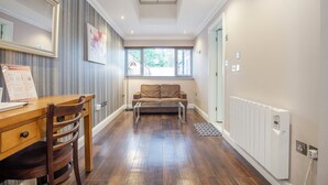 A room with a wooden desk, a brown sofa, a radiator, and a window with blinds. - Marlborough Hotel (Norwich)