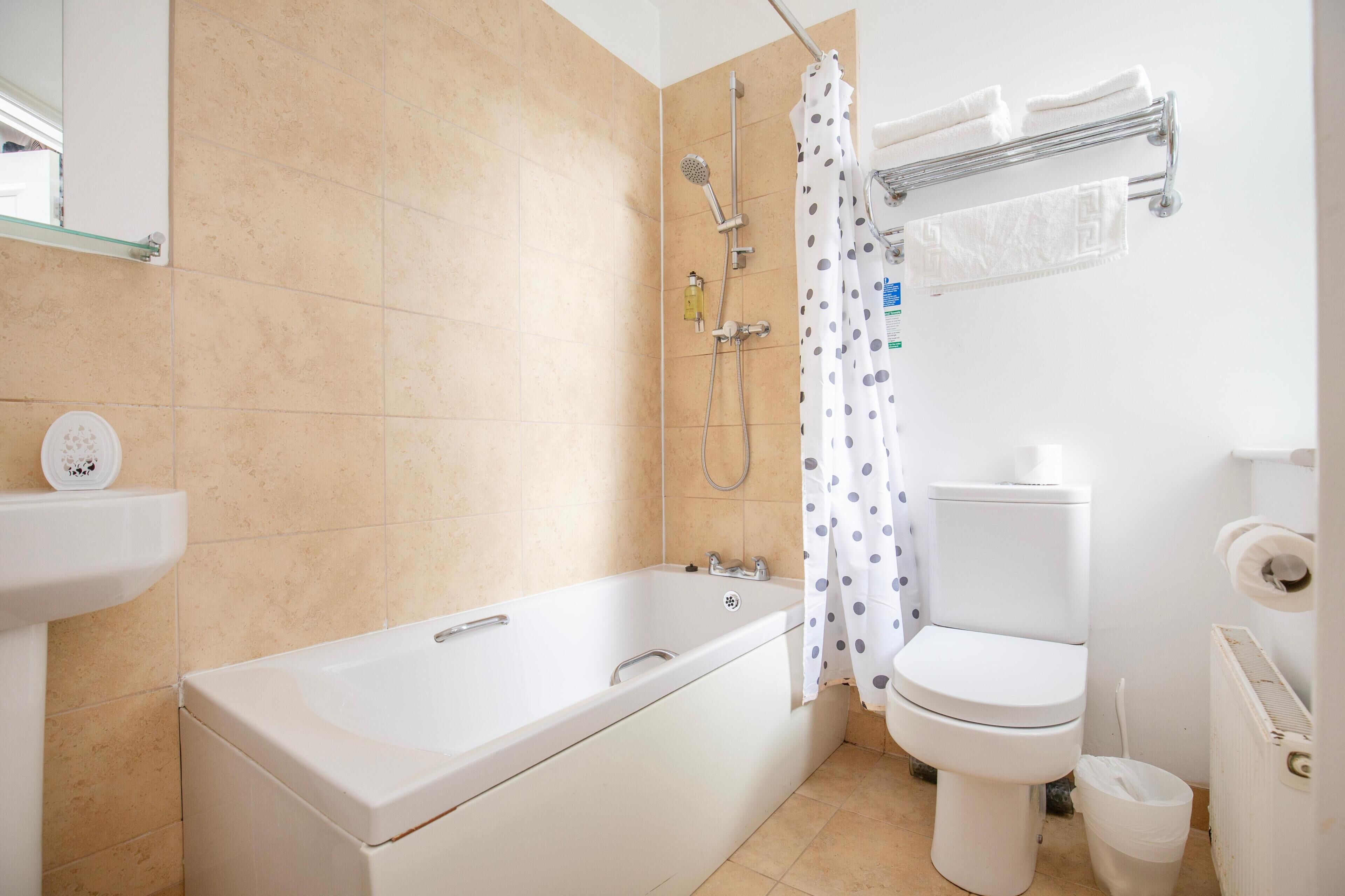 A bathroom with a bathtub, toilet, shower, and a towel rack.