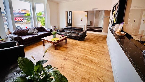 A spacious living room with two leather sofas, a wooden coffee table, and large windows offering a view of the outside. - Marlborough Hotel (Norwich)