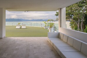 Un balcon avec un canapé blanc, des plantes en pot et une vue sur la mer et les montagnes.