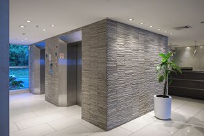 Un espace d’accueil moderne avec un mur à texture, une plante en pot et un comptoir de réception.
