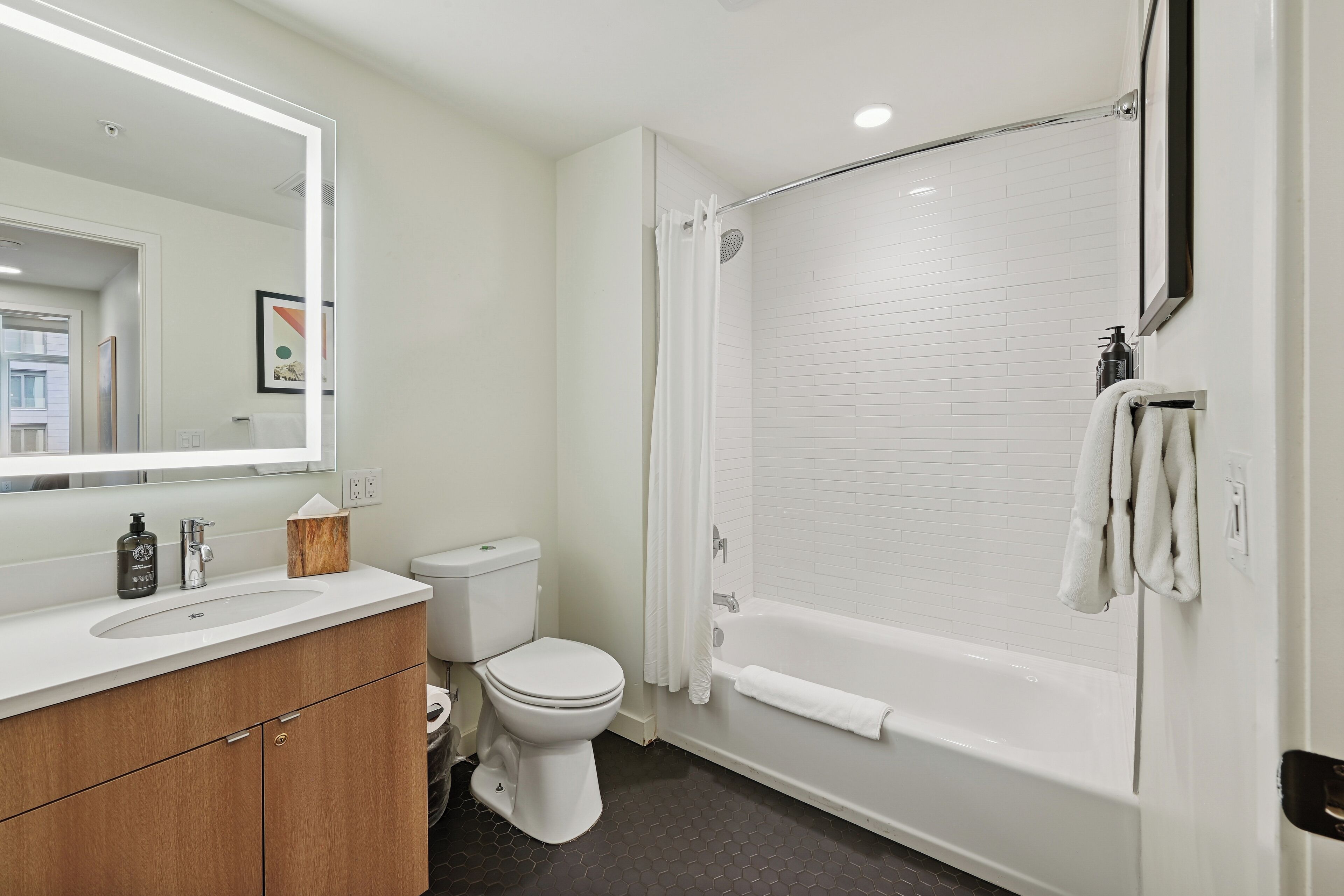 A modern bathroom with a white sink, toilet, and bathtub.