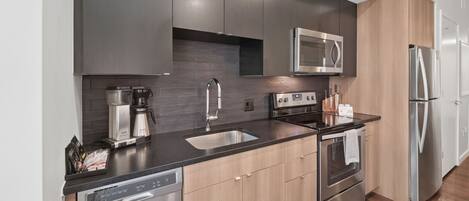 A modern kitchen with stainless steel appliances, a dishwasher, and wooden cabinets.