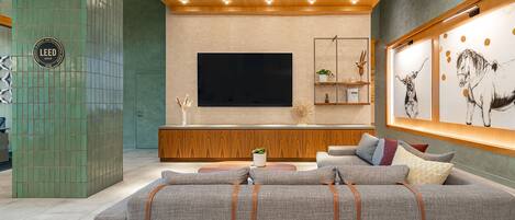 Un soggiorno moderno con un ampio divano grigio, soffitto in legno e televisore a schermo piatto montato a parete.