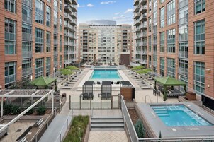 Un moderno edificio de apartamentos con piscina central, zonas de estar al aire libre y un patio bien cuidado.