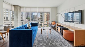 A modern living room with a blue sofa, a round coffee table, and a TV on the wall.