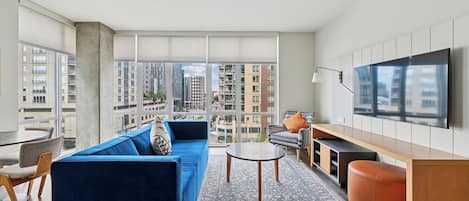 A modern living room with a blue sofa, a round coffee table, and a TV on the wall.