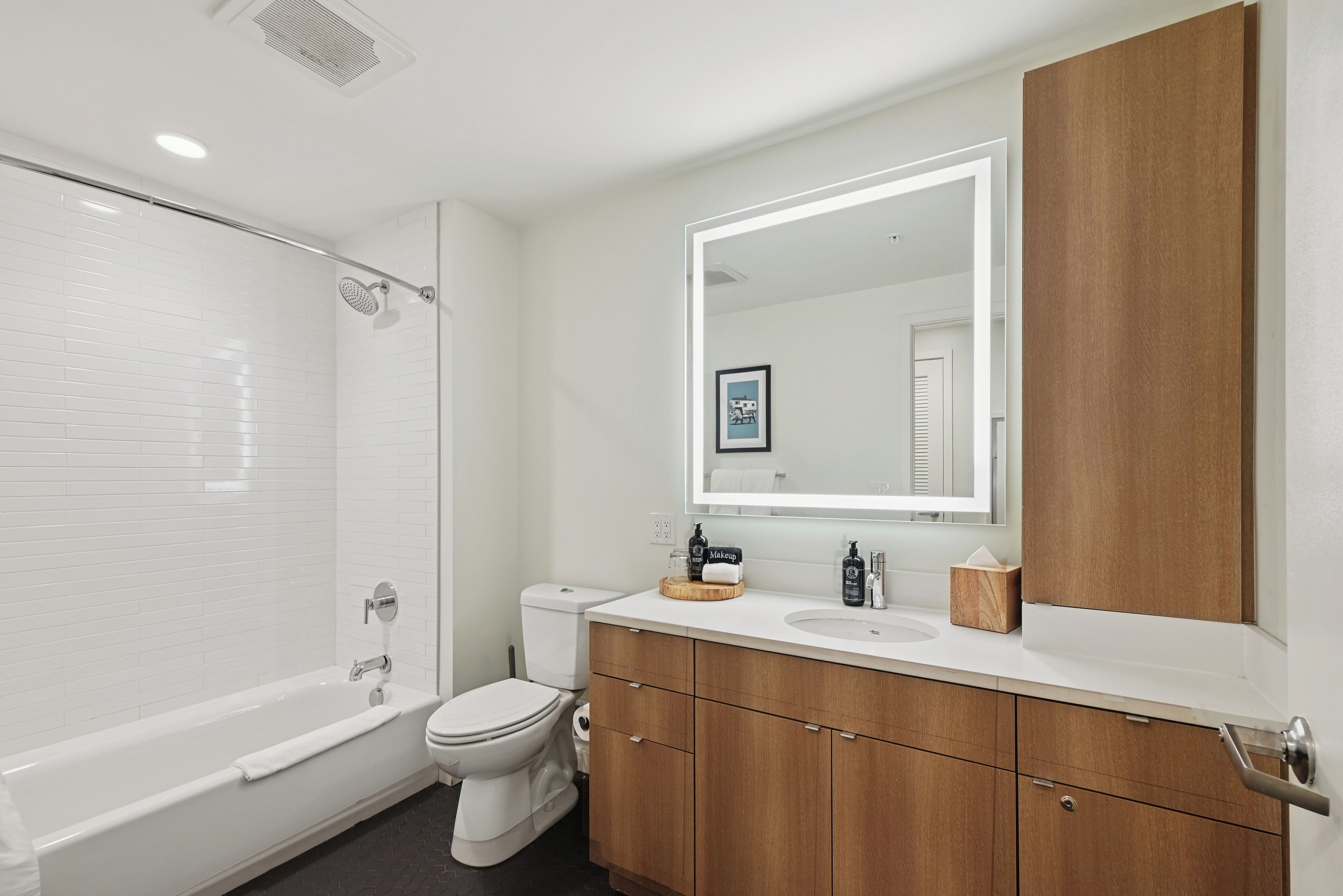 A modern bathroom with a white bathtub, a toilet, and a vanity with a mirror.