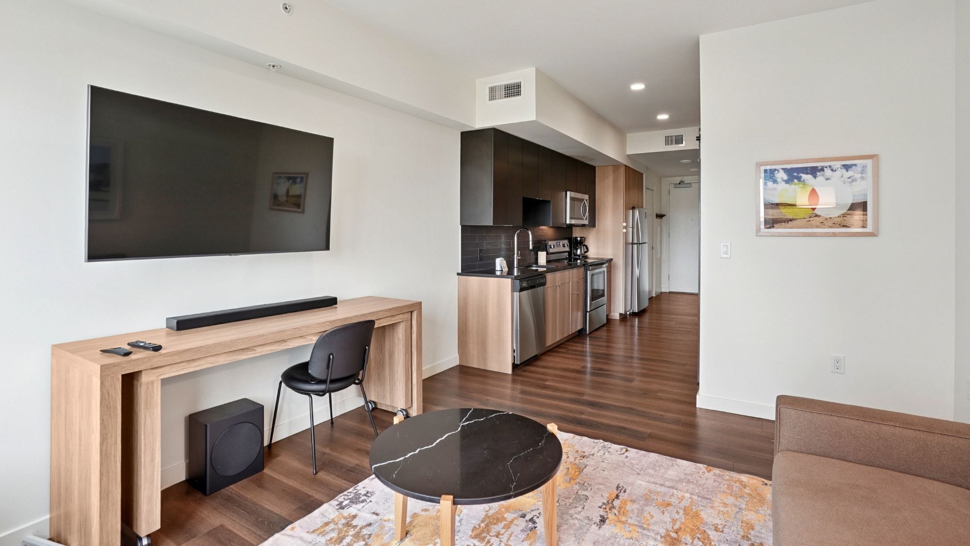 A modern kitchen with a dining area, a flat-screen TV, and a small seating space.