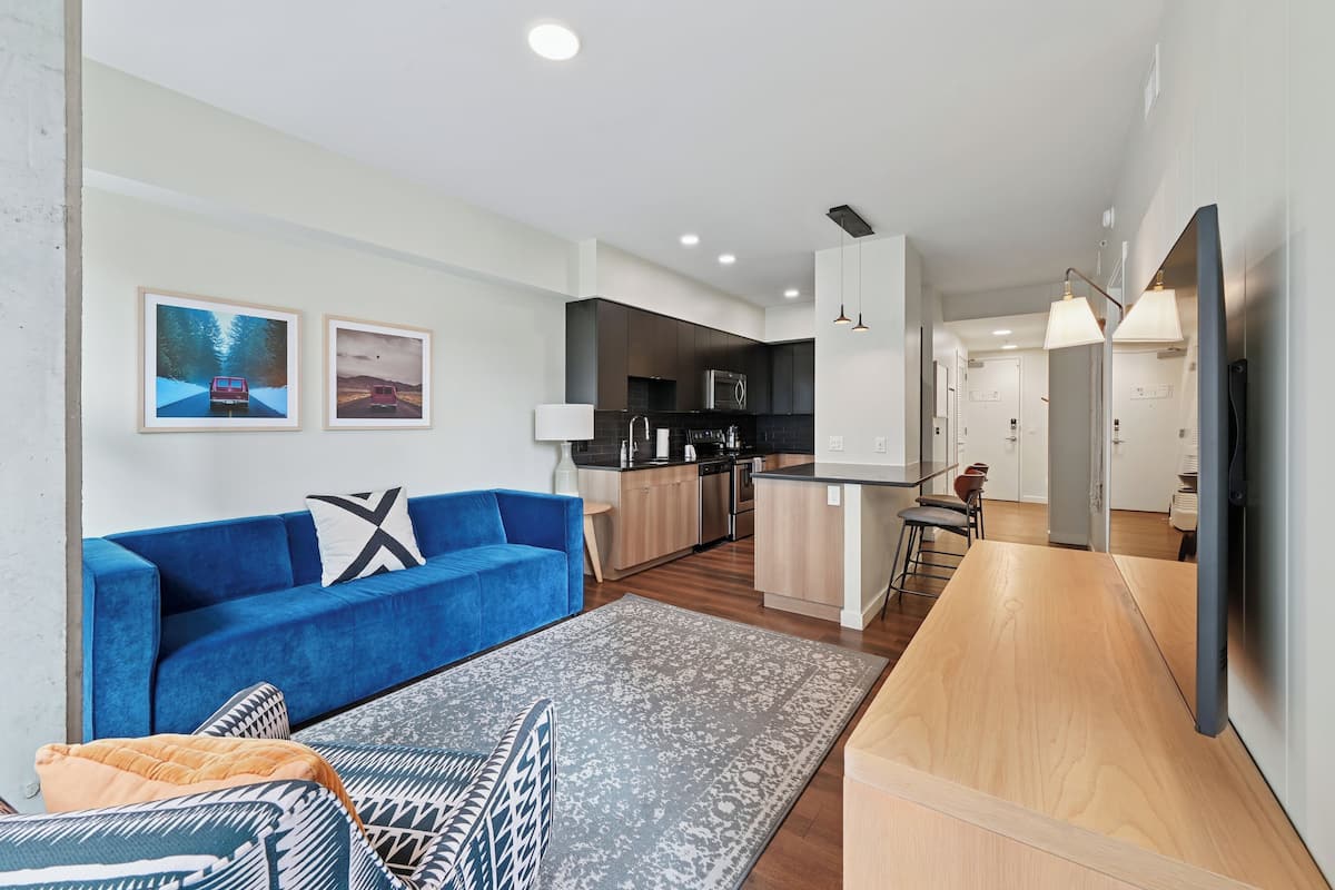 A modern living room with a blue sofa, a patterned rug, and a wooden coffee table.