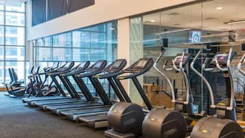 A gym with multiple treadmills and elliptical machines, large windows, and a modern interior design.