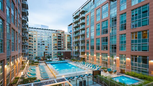 A rooftop pool area with lounge chairs and a smaller pool, surrounded by high-rise residential buildings. - Sentral Union Station (Denver)