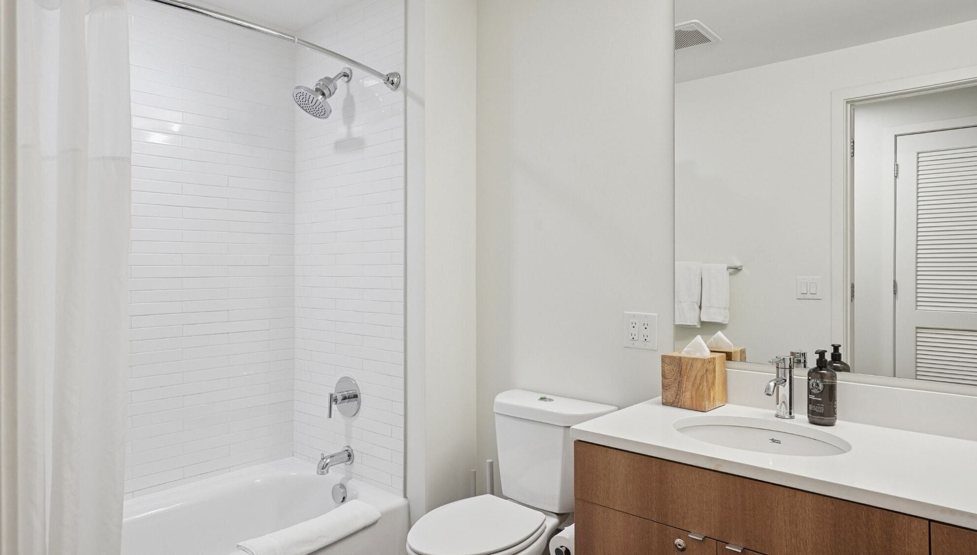 A modern bathroom with a shower, toilet, and sink.