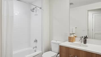 A modern bathroom with a shower, toilet, and sink.
