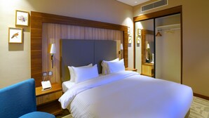 Una camera d'albergo con un letto grande, una scrivania con il telefono, una sedia e un armadio.