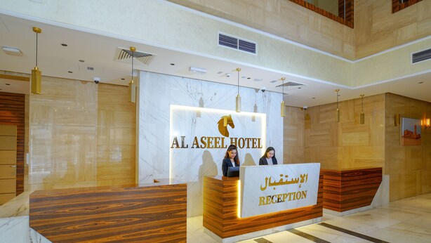 Una reception dell'Hotel Al Aseel con parete in marmo e dettagli in legno.