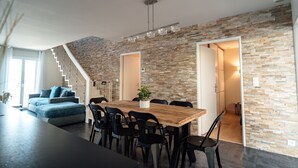 Una cucina moderna con un tavolo da pranzo in legno, sedie nere e una scala che conduce a un altro piano.
