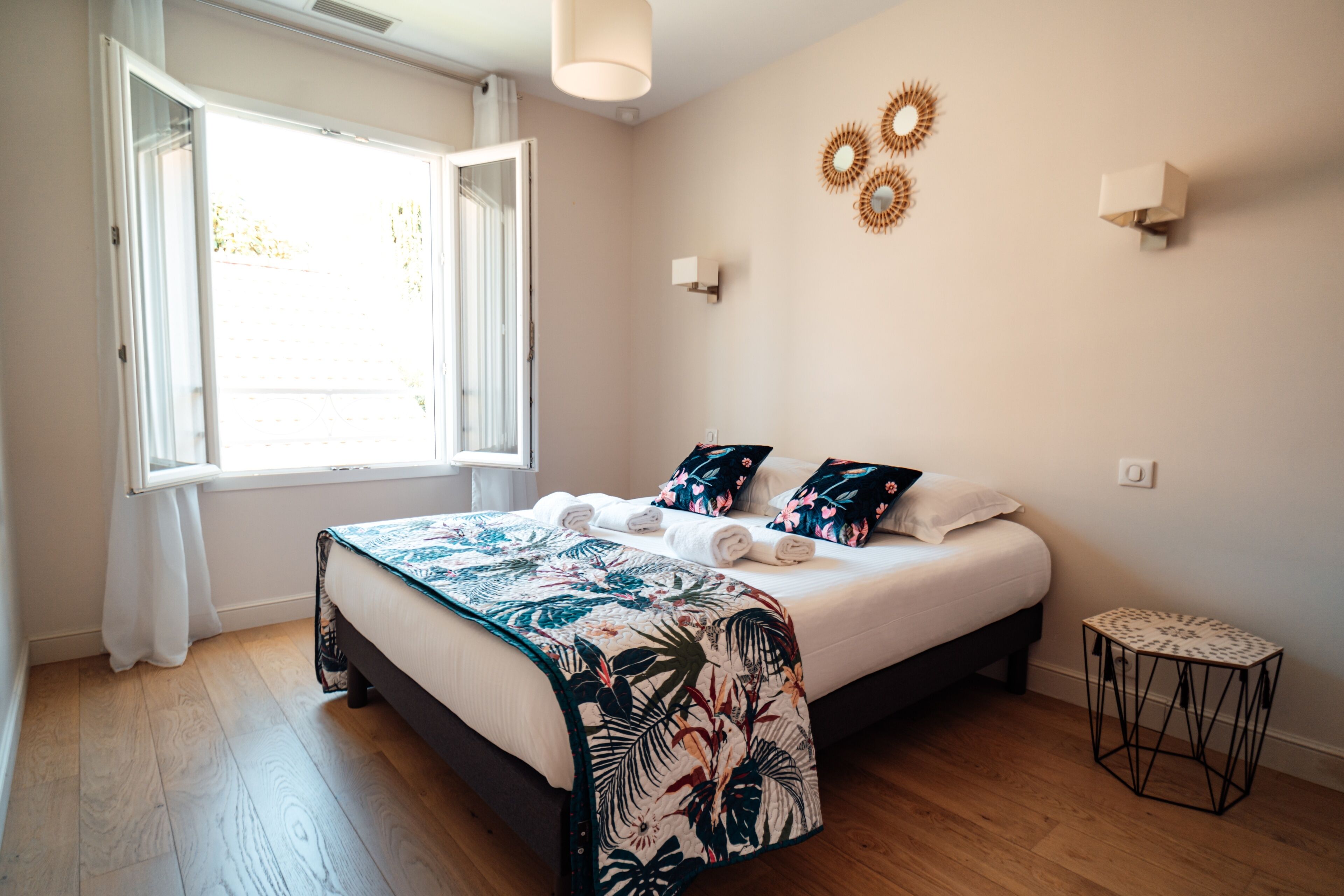 Un dormitorio con cama, ventana, mesita de noche y decoración en la pared.