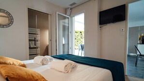 Una camera d'albergo con un letto, un armadio, una TV e un balcone.
