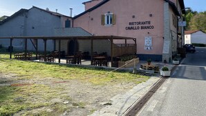 En bygning med et skilt, der viser "RISTORANTE CAVALLO BIANCO", og et udendørs siddeområde med borde og stole.