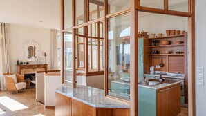 Cocina compacta con armarios de madera, encimera de mármol y vistas al comedor.
