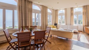 Una habitación amplia con comedor, sofá y grandes ventanales que ofrecen vistas al exterior.