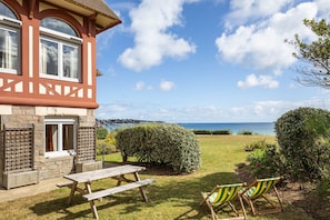 Relax in a serene oceanfront setting with a bay window, picnic table, and comfortable seating.