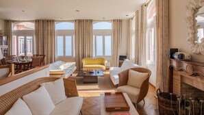 Un salón amplio con un sofá amarillo, sillones blancos, una mesa de centro y una chimenea.