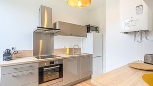 A modern kitchen with stainless steel appliances, a built-in oven, and a microwave. - Le Magda – T2 lumineux entre centre & commerces (Vannes)