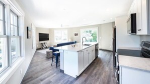 A modern kitchen with a central island, built-in appliances, and a large window providing natural light. - Long Beach Suites: 3 Mins Toes To Sand! (Gloucester)