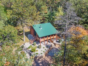 A cabin with a green roof, surrounded by trees and a gravel path. - Private Log Cabin in 10 Acre Forest (Grand Marsh)