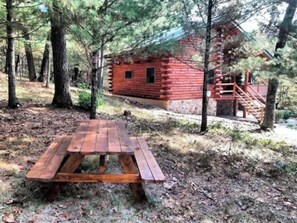 A rustic cabin with a wooden deck and a staircase leading to a deck area. - Private Log Cabin in 10 Acre Forest (Grand Marsh)
