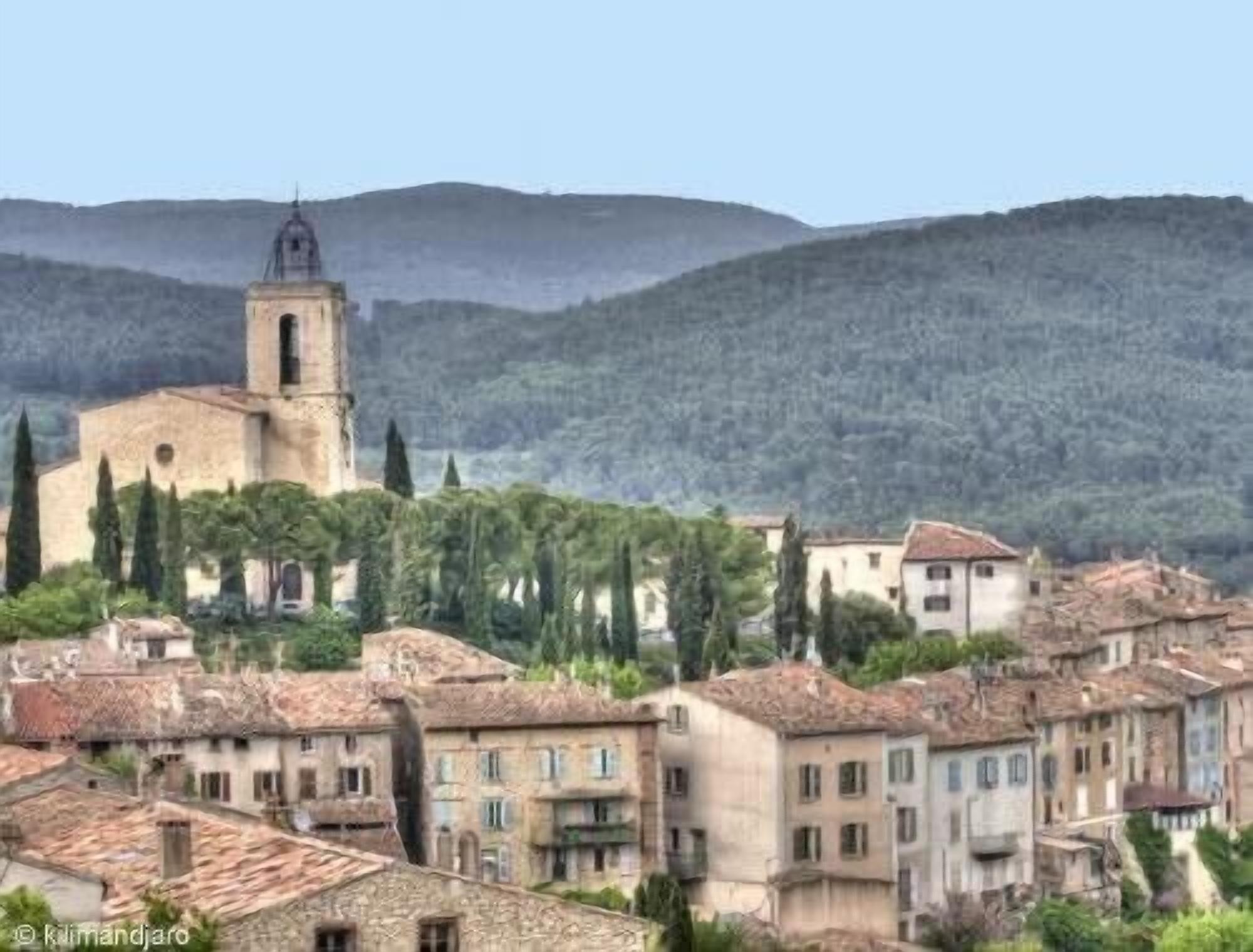 Une ville chargée d’histoire, avec un clocher d’église imposant, des bâtiments traditionnels et un paysage montagneux en toile de fond.