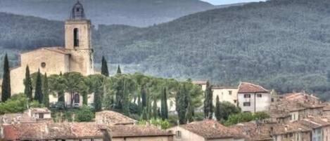 Une ville chargée d’histoire, avec un clocher d’église imposant, des bâtiments traditionnels et un paysage montagneux en toile de fond.