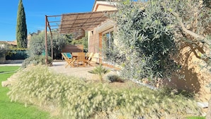 Ein Haus mit Terrasse, Gartenmöbeln und Olivenbäumen.