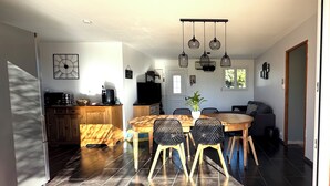 Eine moderne Küche mit Essbereich, ausgestattet mit einem Holztisch, Stühlen und Pendelleuchten.