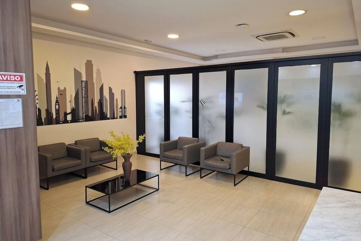 Un espace d’accueil moderne agrémenté d’une fresque représentant un paysage urbain, d’un comptoir de réception et d’un coin salon avec des canapés et une table basse.