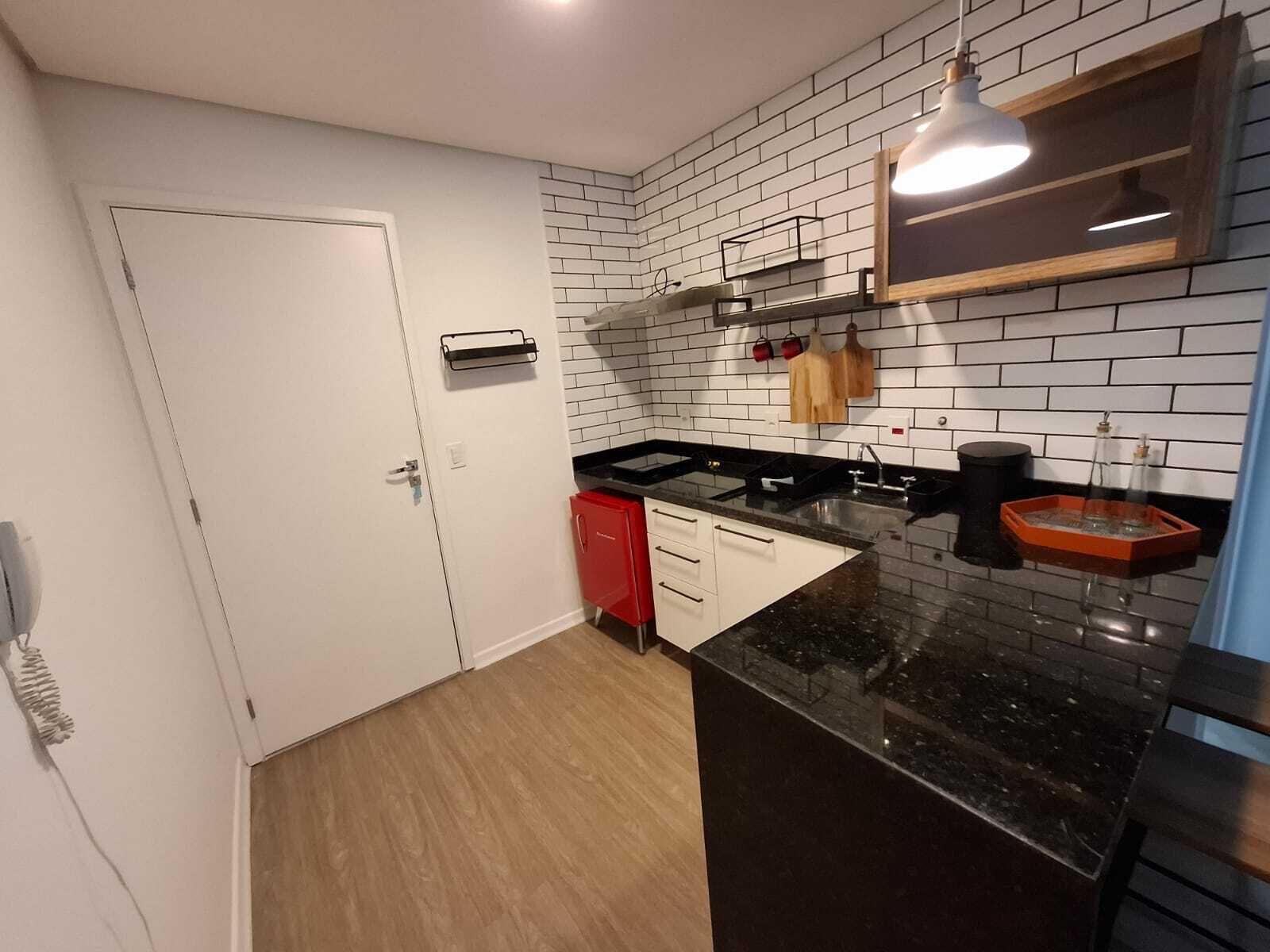 A modern kitchen with white cabinets, a black countertop, and a tiled backsplash.
