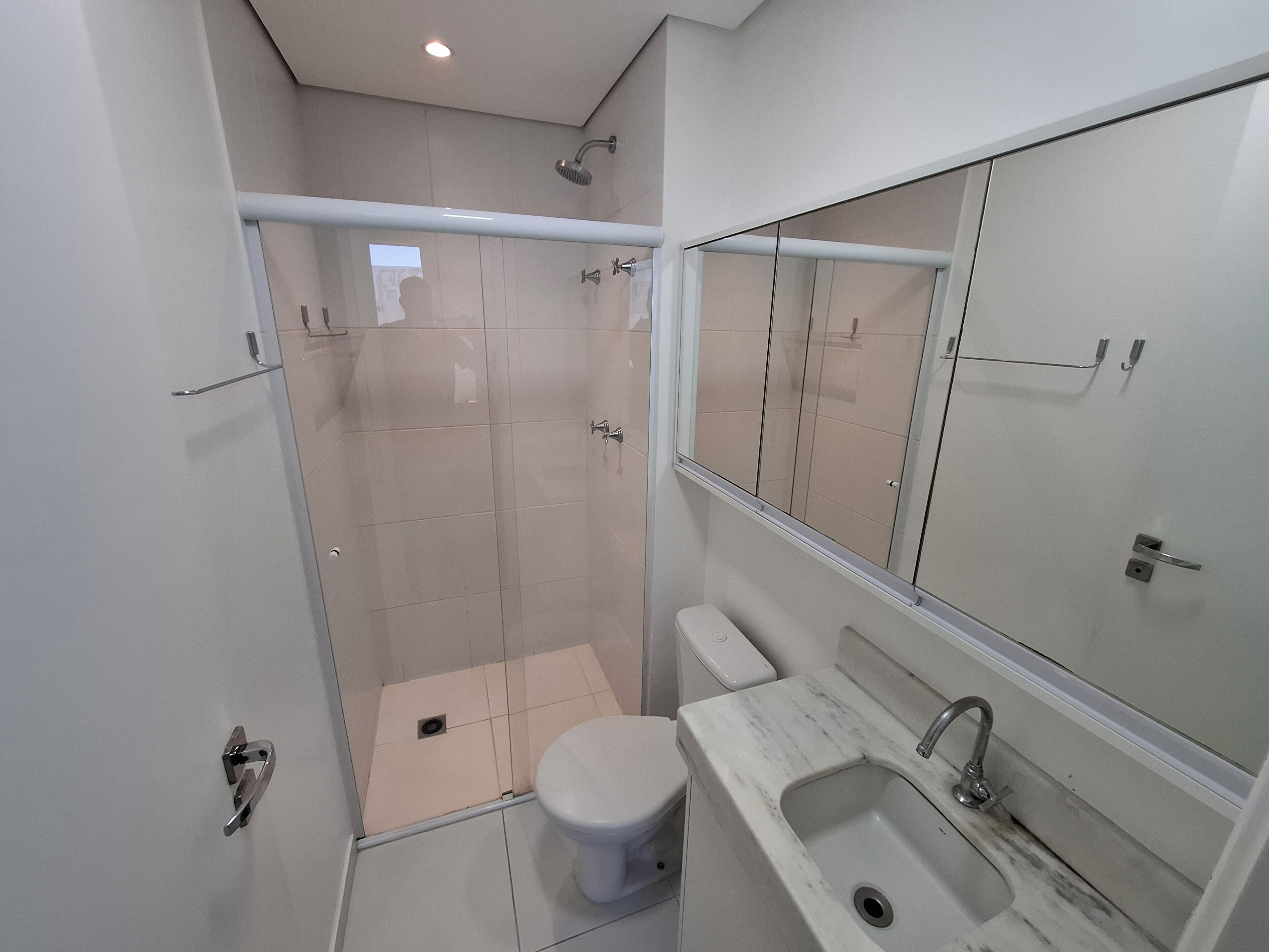 A modern bathroom with a glass-enclosed shower, a toilet, and a sink with a mirror above.